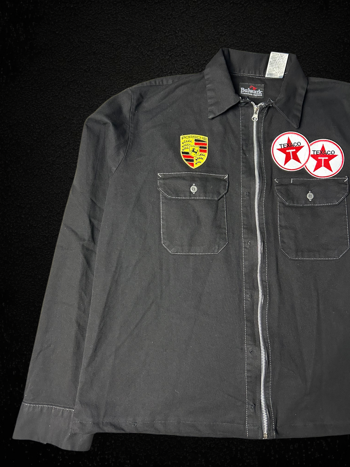 Camino’s Auto Parts reworked black cotton trucker jacket featuring Porsche and Texaco patches with a front zipper