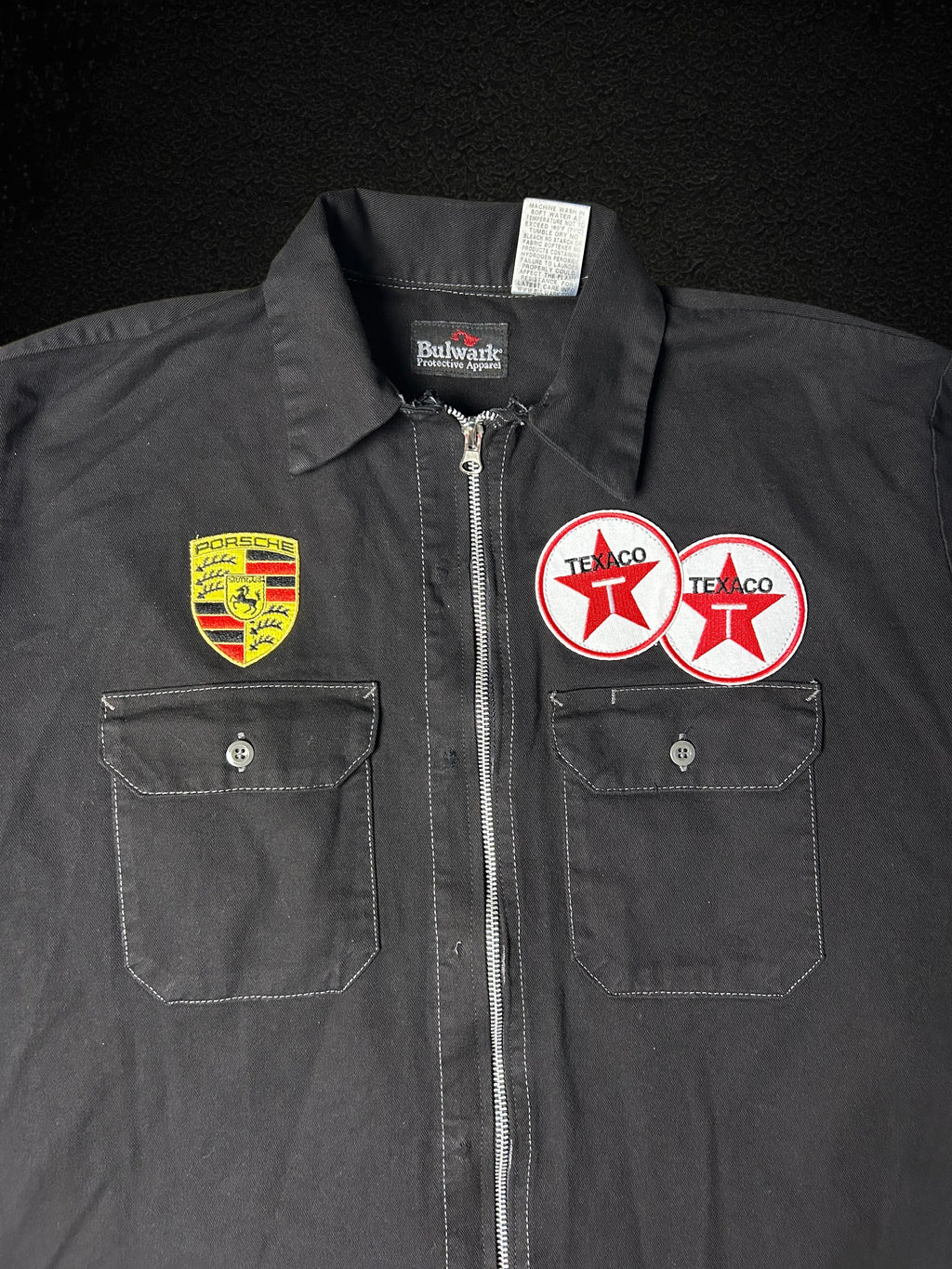 Camino’s Auto Parts upcycled black work shirt reworked into a zipper jacket with Porsche and Texaco patches.
