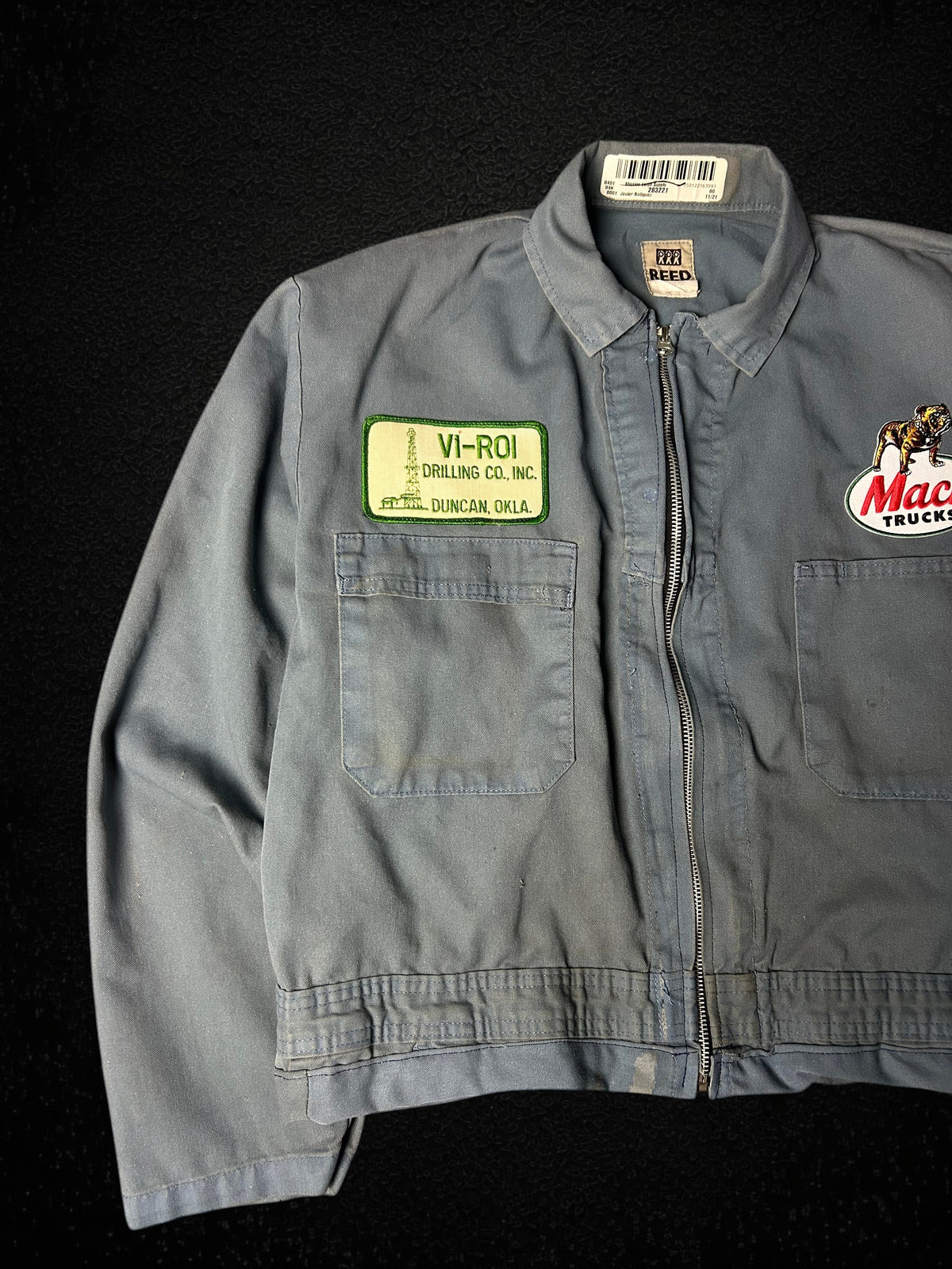 Camino’s Auto Parts upcycled grey Mack Truck trucker jacket with vintage patches and distressed detailing.