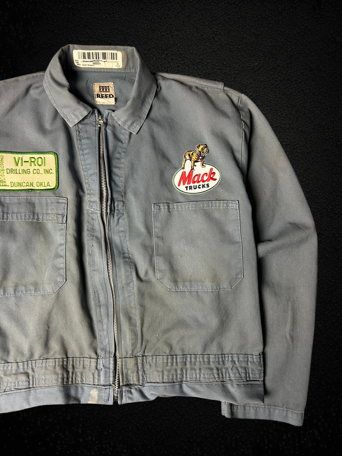 Camino’s Auto Parts upcycled grey Mack Truck trucker jacket with vintage patches and distressed detailing.